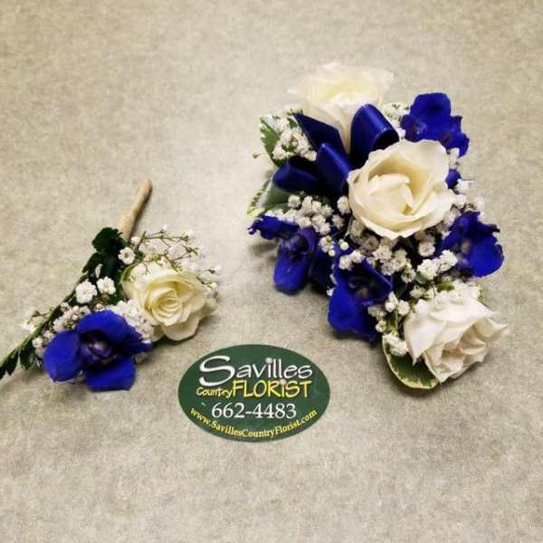 Two blue and white floral corsages with roses and baby's breath.