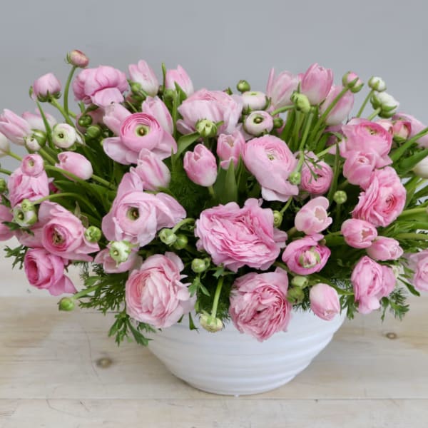Pink ranunculus bouquet in a white bowl vase