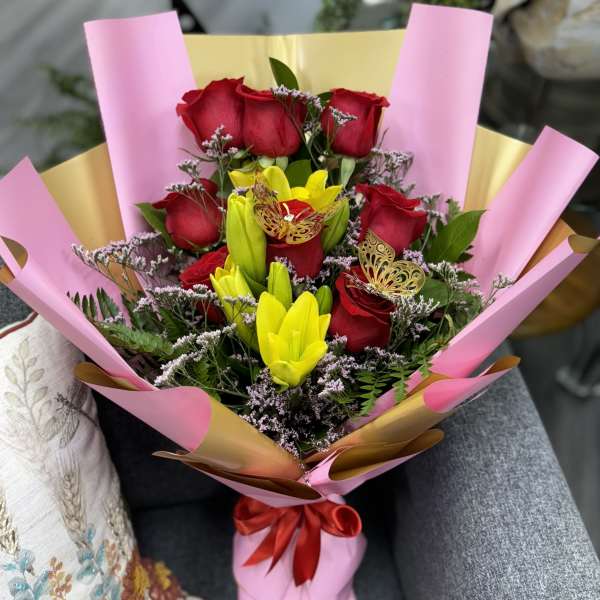 Bouquet of red roses and yellow lilies wrapped in pink paper