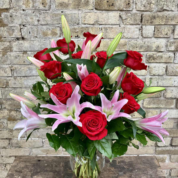Red roses and pink lilies arranged in a clear glass vase