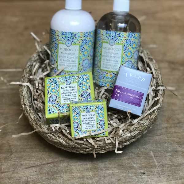 Spa gift basket with soap, lotion, and a candle in a woven tray