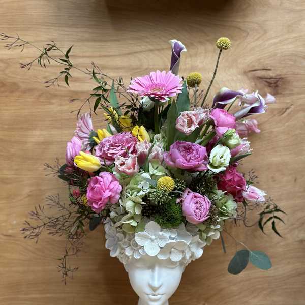 Pink and white floral arrangement in a white face vase