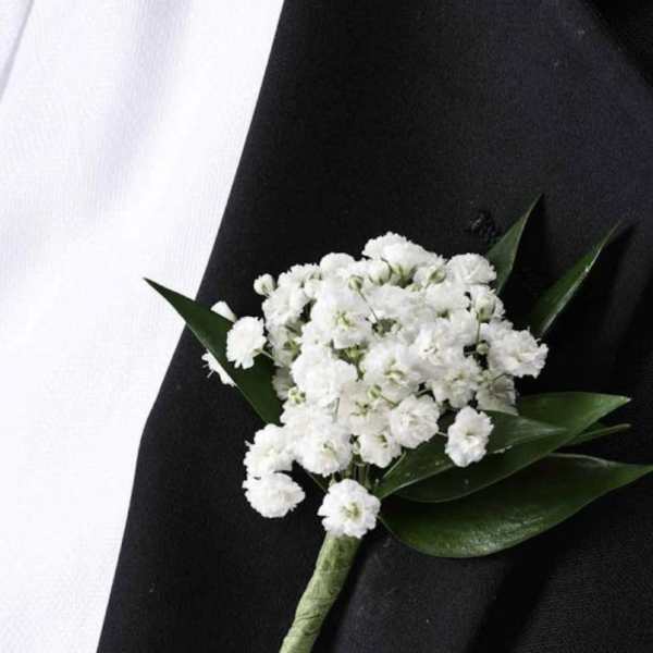 White boutonniere with small clustered flowers and dark green leaves