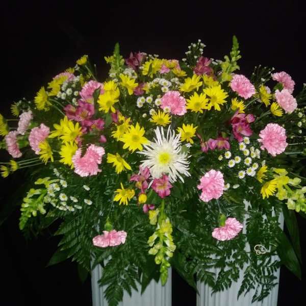 Large floral arrangement with pink and yellow flowers in a white container