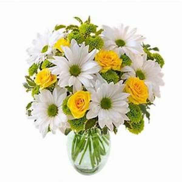 Bouquet of white daisies and yellow roses in a clear glass vase
