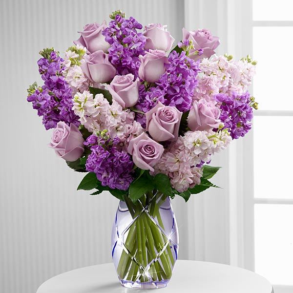 Lavender roses and purple flowers in a clear vase