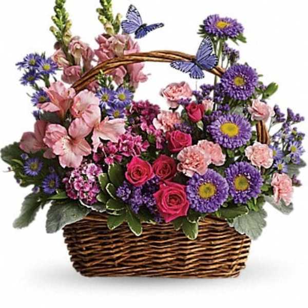 Basket arrangement of pink and purple flowers with butterfly picks