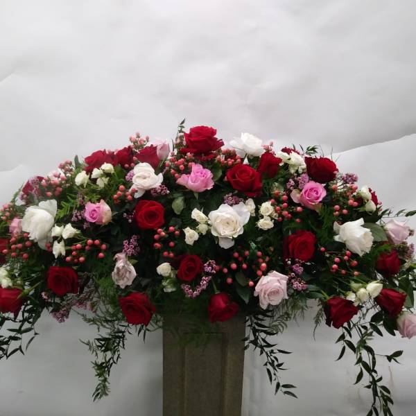 Large arrangement of red, white, and pink roses in a tall vase