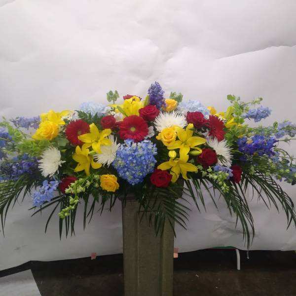 Large mixed flower arrangement with roses, lilies, daisies, and blue blooms