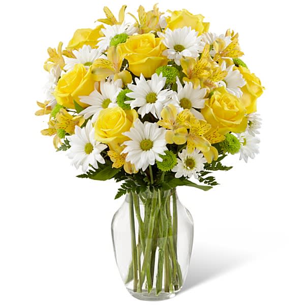 Yellow roses and white daisies in a clear glass vase
