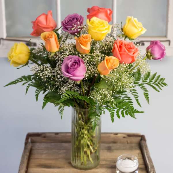 Colorful roses in a clear glass vase with baby's breath