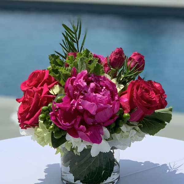 Pink roses and a magenta peony in a clear glass vase