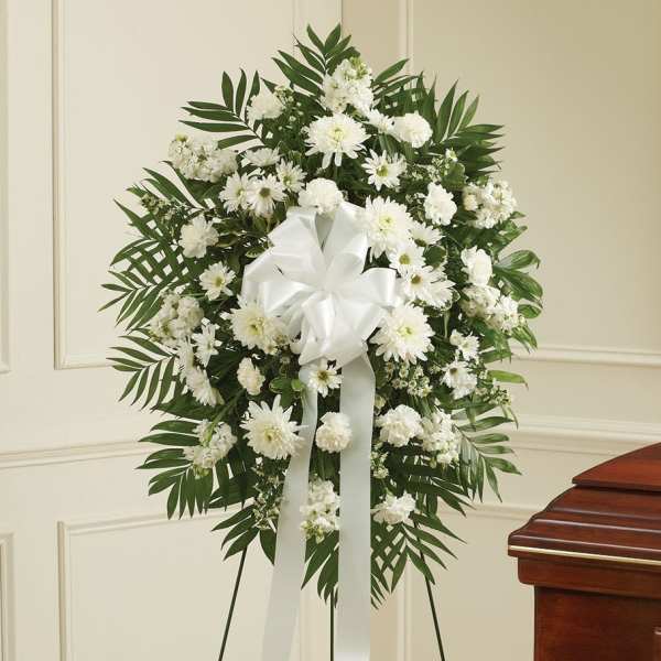 White funeral wreath with daisies and carnations on a stand