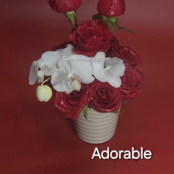 Red roses and white orchids arranged in a white vase