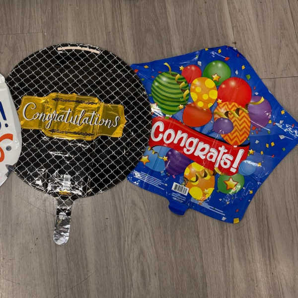 Three round congratulatory balloons lie on a floor.