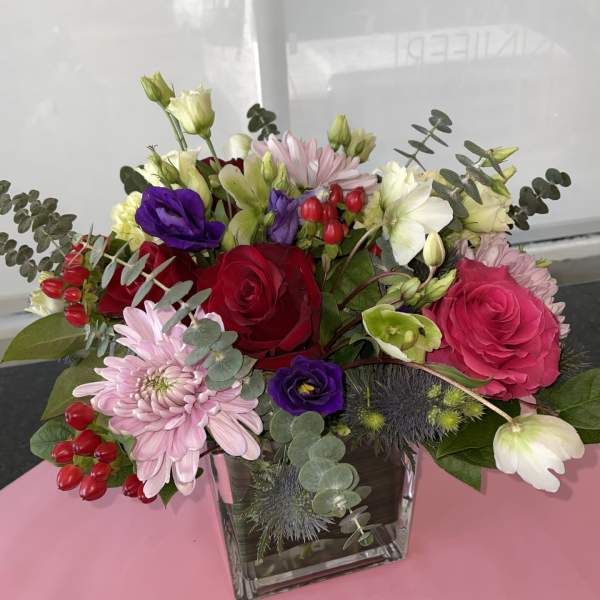 Mixed bouquet of roses, lisianthus, and chrysanthemums in a glass vase