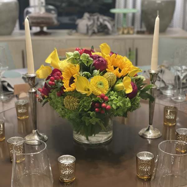 Bright yellow and magenta floral centerpiece in a glass vase on a table