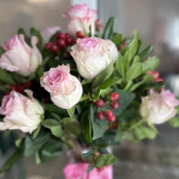 Bouquet of pale pink roses with red berries and a pink ribbon