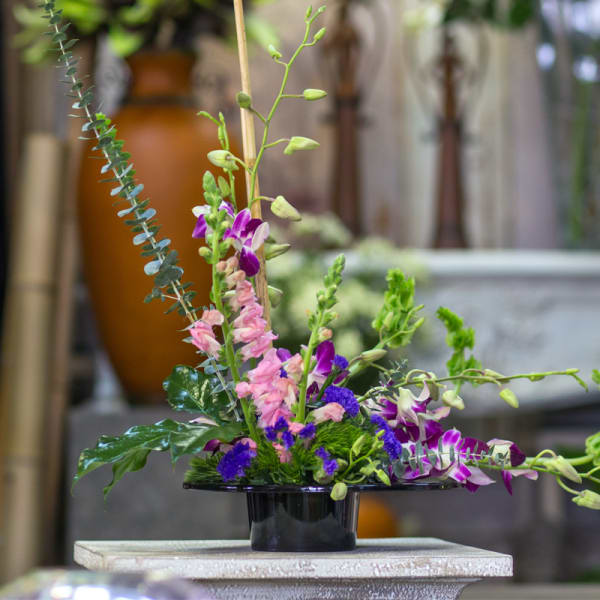 Purple and pink orchid arrangement in a black vase
