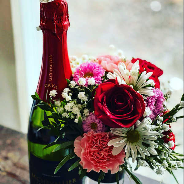 Red champagne bottle with a small bouquet of pink and white flowers