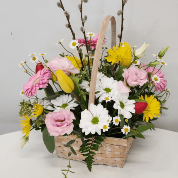 Basket arrangement of daisies, tulips, and pink blooms with pussy willow stems