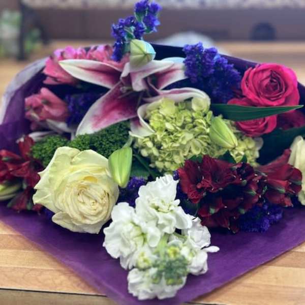 Mixed bouquet with lilies, roses, and hydrangea in purple wrap