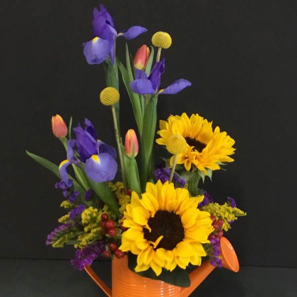 Sunflowers and purple irises arranged in an orange watering can