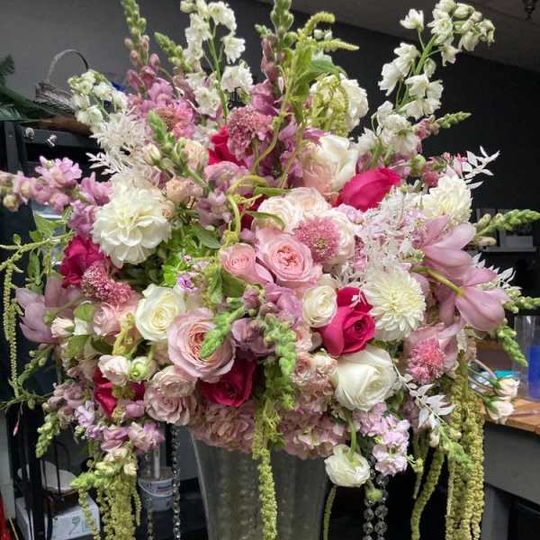 Large pink and white floral arrangement in a tall glass vase