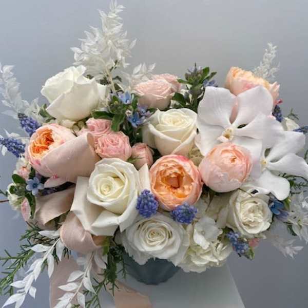 Bouquet of white and blush roses with white orchids in a vase