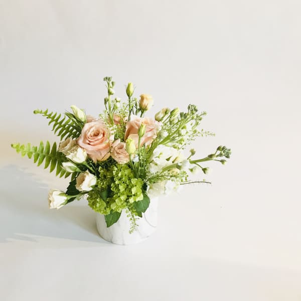 Peach and white floral arrangement in a white vase