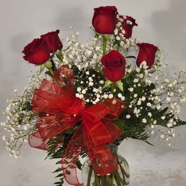 Red roses with baby's breath in a glass vase and red ribbon
