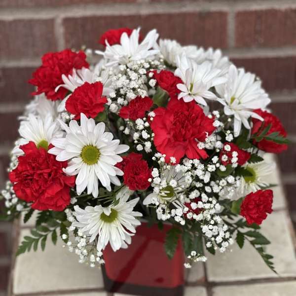 Red carnations and white daisies in a red container