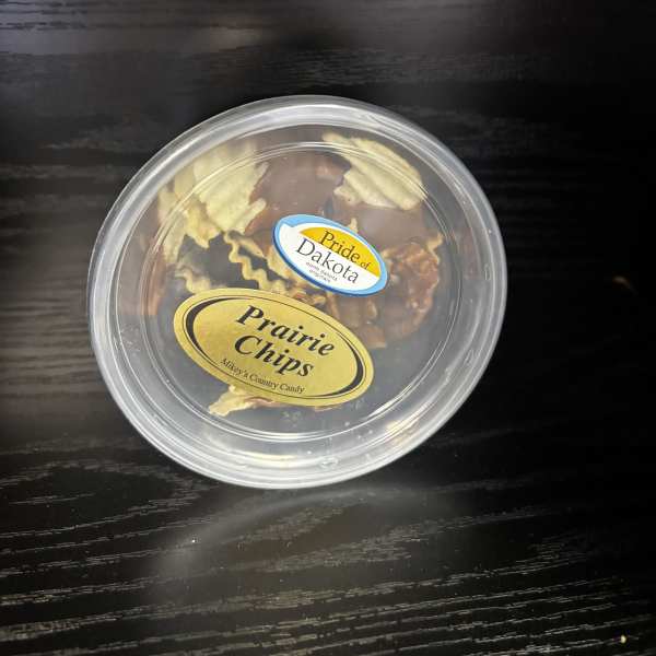 Round plastic tub of assorted candy on a dark table