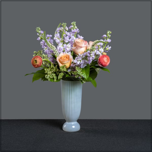 Lavender flowers and peach roses in a tall white vase