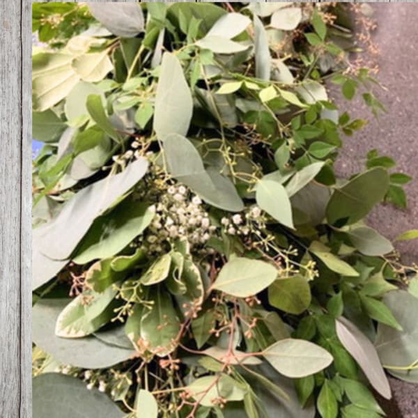 Loose bundle of assorted green foliage with small white filler flowers