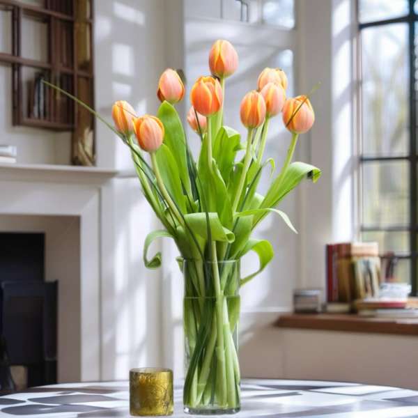 Orange tulips in a clear glass vase on a table