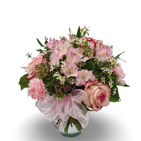 Pink mixed flower bouquet in a glass vase with a pink ribbon