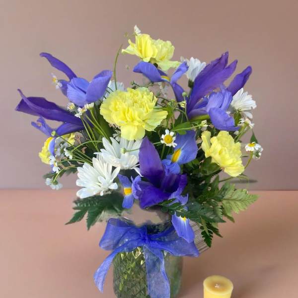 Blue and yellow bouquet in a glass vase with a ribbon