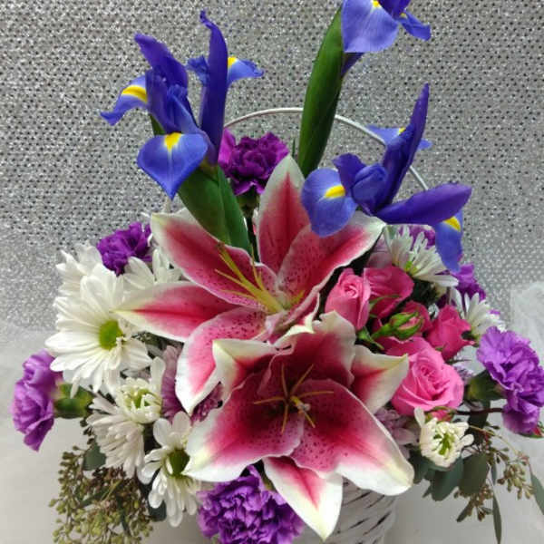 Basket arrangement with pink lilies, blue irises, and white daisies