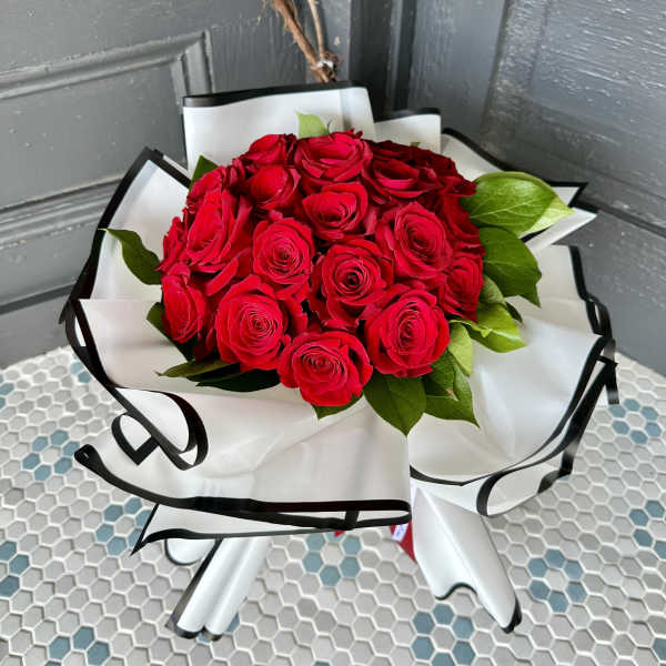 Bouquet of red roses wrapped in white paper with black trim