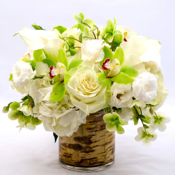 White and green floral arrangement in a birch-pattern vase