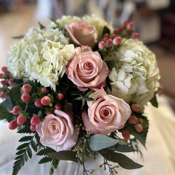 Bouquet of pink roses and white hydrangeas with berry accents