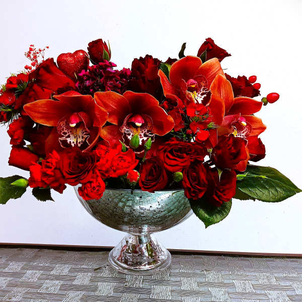 Red floral arrangement in a glass pedestal bowl