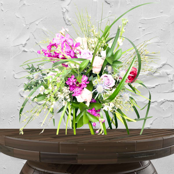 Pink and white mixed flower arrangement in a low wooden container