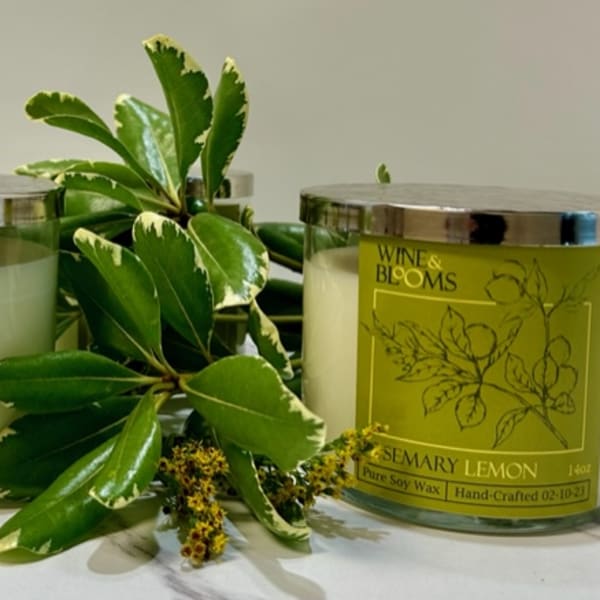 Two rosemary lemon candles with a potted plant between them