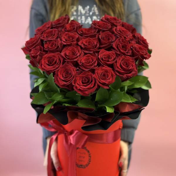 Large bouquet of red roses in a red hatbox with ribbon