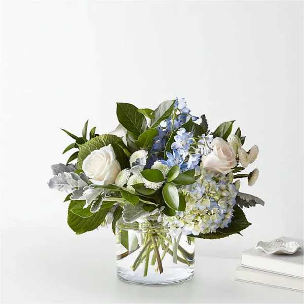White roses and blue flowers in a clear glass vase