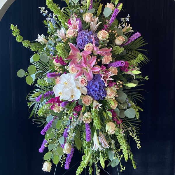 Large standing floral spray with pink lilies, roses, orchids, and purple blooms