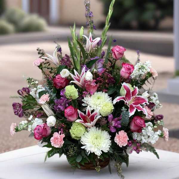 Mixed bouquet in a basket with pink roses, lilies, and white chrysanthemums