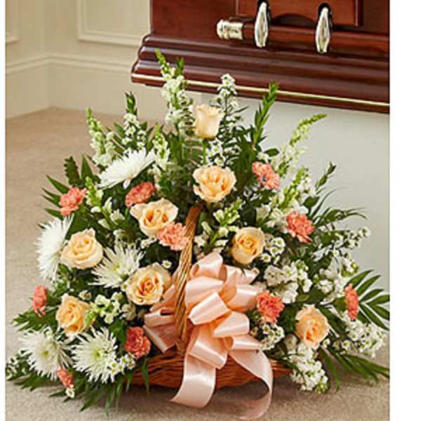 Basket arrangement of peach and white flowers with a pink ribbon